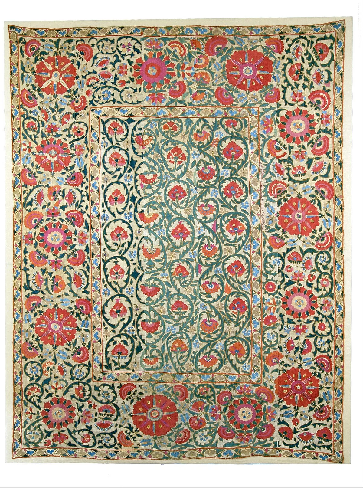 Geborduurd wandkleed met rode bloemen en groene ranken op een crèmekleurige ondergrond.